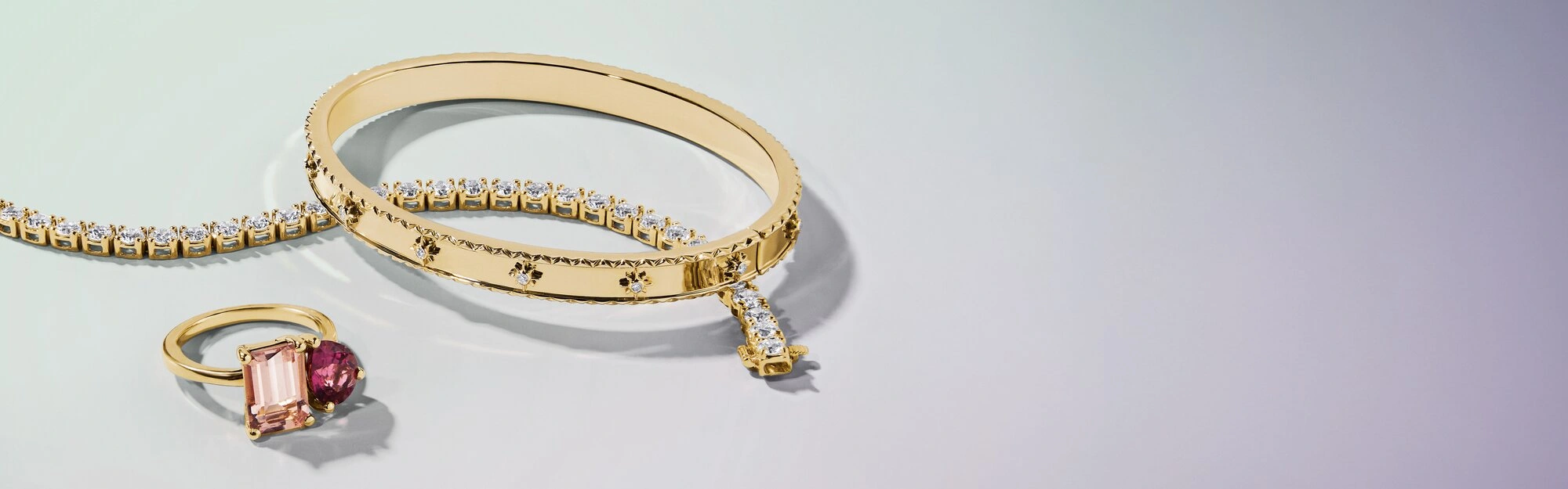 Gold diamond tennis bracelet, bangle, and gemstone cocktail ring.