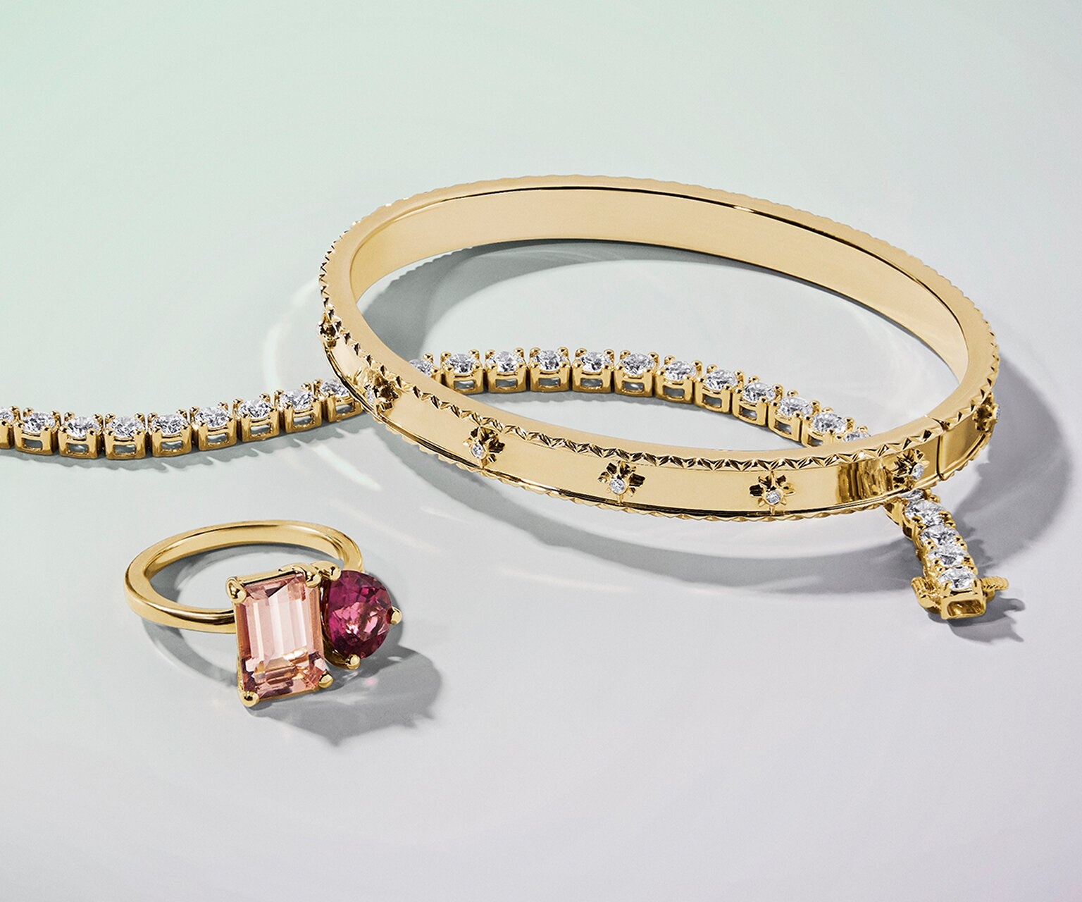 Gold diamond tennis bracelet, bangle, and gemstone cocktail ring.